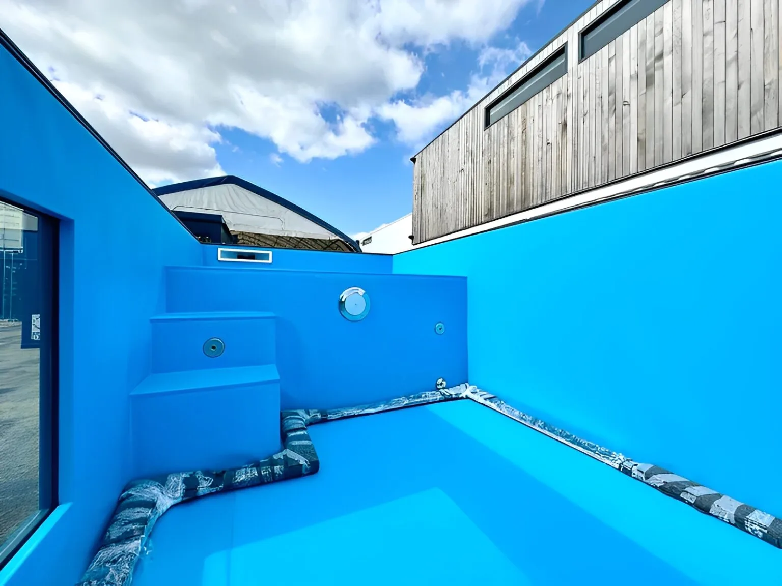 Steel-framed shipping container pool with viewing windows and custom decking
