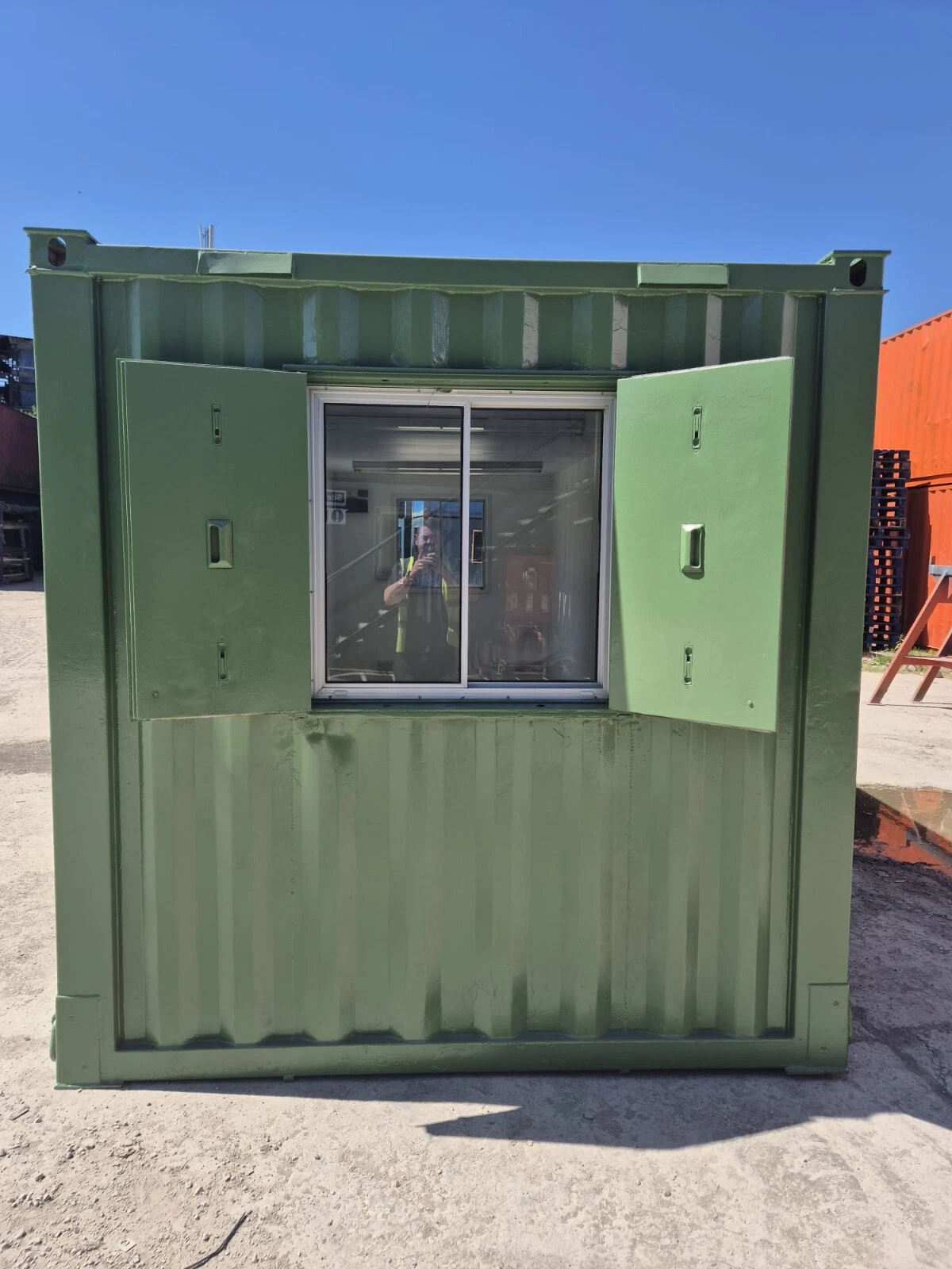 Open-plan container office with windows, electrical installation, and secure steel door