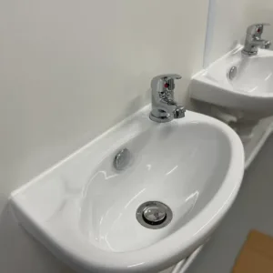 Portable container restroom unit with complete plumbing and electrical installation