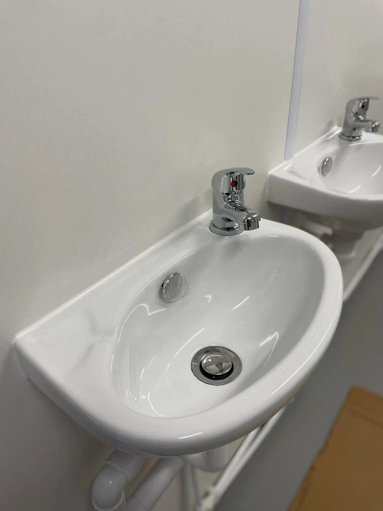 Portable container restroom unit with complete plumbing and electrical installation